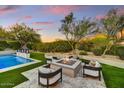 Cozy fire pit area with modern seating, adjacent to the refreshing pool area, surrounded by serene landscaping at 9939 E Desert Jewel Dr, Scottsdale, AZ 85255