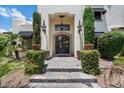 Elegant entry with arched doorway, wrought iron door, pendant lights, and stone steps amid lush landscaping at 13250 N 13Th Ln, Phoenix, AZ 85029