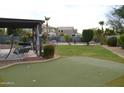 Lush backyard showcasing a covered patio, built-in putting green and mature landscaping at 13486 W Evans Dr, Surprise, AZ 85379