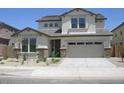 View of a two-story home with stone accents, a two-car garage, and a well-maintained front yard at 14150 W Boca Raton Rd, Surprise, AZ 85379