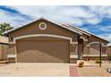 Close-up view of the two-car garage, showing the front entryway and desert landscaping at 15980 W Smokey Dr, Surprise, AZ 85374