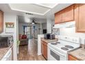 Open kitchen with wood cabinets and white appliances, seamlessly flowing into the living area with patio access at 16602 N 25Th St # 204, Phoenix, AZ 85032