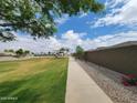 Well-maintained community park with sidewalk, grassy area, and playground in the background at 19422 N Fiano Dr, Maricopa, AZ 85138