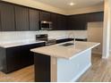 Modern kitchen featuring sleek black cabinetry, stainless steel appliances, a center island, and white subway tile backsplash at 7229 E Cattle Call St, San Tan Valley, AZ 85143