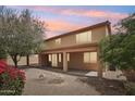 Backyard with covered patio, desert landscaping, and mature trees providing shade and privacy at 7546 W Mary Jane Ln, Peoria, AZ 85382