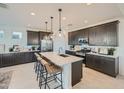 Stylish kitchen featuring a central island with seating and pendant lights, alongside dark cabinets and modern appliances at 8251 E Petunia Ave, Mesa, AZ 85212