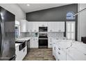 Modern kitchen with white cabinets, stainless steel appliances, quartz countertops, and hardwood floors at 8913 S Forest Ave, Tempe, AZ 85284