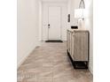 Bright hallway featuring tile flooring and an accent cabinet with decor at 19968 W Flower St, Buckeye, AZ 85396