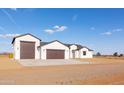 Modern home exterior with multi-car garage featuring a spacious driveway and well-maintained desert landscaping at 34449 N Elk Run Rd, San Tan Valley, AZ 85143