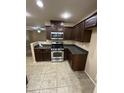 Compact kitchen with stainless steel appliances, tiled flooring, and dark wood cabinetry at 40246 W Hopper Dr, Maricopa, AZ 85138