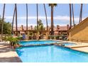 Resort-style pool with lush landscaping, pergola with lounge chairs, and blue tiled trim at 4901 S Calle Los Cerros Dr # 220, Tempe, AZ 85282