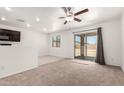 Spacious living room with ceiling fan and sliding glass doors leading to the backyard at 8577 S 253Rd Dr, Buckeye, AZ 85326