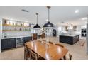 Open-concept dining and kitchen area with stylish lighting fixtures and a bar area at 9005 W Villa Chula St, Peoria, AZ 85383