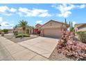 Single-Gathering home with desert landscaping, a two-car garage, flowering cactus, and a well-manicured lawn at 15534 W Big Sky Dr, Surprise, AZ 85374