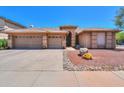 A beige house exterior boasts a three-car garage, desert landscaping, and tiled roof at 4560 E Paso Trl, Phoenix, AZ 85050