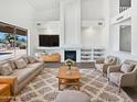 Spacious living room with a cozy fireplace, plush seating, and view of the pool at 5501 W Whispering Wind Dr, Glendale, AZ 85310