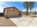 Tan single-story home with a two-car garage, desert landscaping, and a concrete driveway in a residential neighborhood at 681 W Racine Loop, Casa Grande, AZ 85122