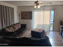 View of living room with sliding glass door to patio, ceiling fan, and tile flooring at 7118 S 37Th Gln, Phoenix, AZ 85041