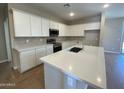 Bright kitchen featuring white cabinets, gray backsplash, stainless appliances, an island and quartz countertops at 7243 E Cattle Call St, San Tan Valley, AZ 85143