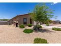 The exterior of this desert home boasts low-maintenance landscaping, gravel, and a shade tree to add natural beauty at 8012 S Magic Dr, Casa Grande, AZ 85193