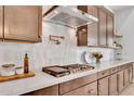 Close up of modern gas range with pot filler faucet, custom cabinets, white subway tile backsplash, and quartz countertop at 10006 E Rotation Dr, Mesa, AZ 85212