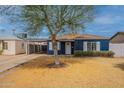Charming blue home featuring white trim accents, a mature tree, and a driveway leading to a carport at 1622 N 17Th Ave, Phoenix, AZ 85007