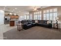 Open-concept living room with plush carpeting, natural light, and a spacious black leather sectional sofa at 18226 W Stinson Dr, Surprise, AZ 85374