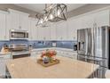 Modern kitchen with stainless steel appliances, marble countertop island, and sleek white cabinetry at 21266 S 213Th Pl, Queen Creek, AZ 85142