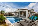 Inviting backyard features a sparkling pool, lounge chairs, patio area, and verdant landscaping at 23503 S 228Th Pl, Queen Creek, AZ 85142