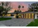 A stylish single-story home with a brick driveway, modern garage door, and basketball hoop at 26 W Morten Ave, Phoenix, AZ 85021
