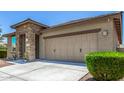 Beautiful home showcasing a stone-accented entrance, a two-car garage, and manicured landscaping at 41825 W Mesquite Rd, Maricopa, AZ 85138