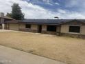 Single-story home featuring stone accents, desert landscaping, and modern solar panels on the roof at 5542 W Monte Cristo Ave, Glendale, AZ 85306