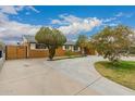 Suburban home with a large concrete driveway, mature trees, and a secure fenced yard at 6837 W Camelback Rd, Phoenix, AZ 85033