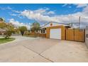 Inviting home showcasing a spacious driveway, gated yard, and attached garage at 6837 W Camelback Rd, Phoenix, AZ 85033