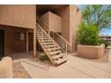 Exterior view of a tan building with concrete walkway and staircase leading to upper level condos and desert landscaping at 8155 E Roosevelt St # 205, Scottsdale, AZ 85257