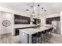 Modern kitchen with a large island, stainless steel appliances, dark cabinets, and stylish pendant lighting at 9448 W Villa Hermosa --, Peoria, AZ 85383