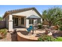 Landscaped backyard featuring a patio with outdoor seating, desert vegetation and an outdoor ceiling fan at 31716 N Poncho Ln, San Tan Valley, AZ 85143