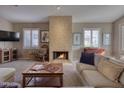Cozy living room with a stone fireplace, plush seating, and plenty of natural light through plantation shutters at 3212 E Desert Cove Ave, Phoenix, AZ 85028