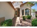 Inviting entryway with a wooden front door, lush landscaping, and a well-lit walkway at 35746 N 32Nd Ln, Phoenix, AZ 85086