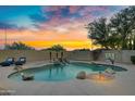Stunning pool area with a rock waterfall feature, lush palm trees, and comfortable lounge chairs at 4329 W Electra Ln, Glendale, AZ 85310