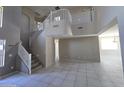Spacious living area featuring high ceilings, tile flooring, and a grand staircase to the second floor at 43455 W Chisholm Dr, Maricopa, AZ 85138