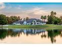 Stunning exterior view of luxury home with waterfront access, lush landscaping, and sunset reflections on a serene lake at 5 E Oakwood Hills Dr, Chandler, AZ 85248