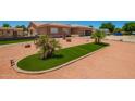 Home showcases a unique yard with modern xeriscaping featuring artificial turf and young palm trees at 10535 W San Miguel Ave, Glendale, AZ 85307