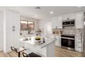 Bright kitchen boasts white cabinets, stainless appliances, backsplash and an island with stylish place settings at 10625 E Bramble Ave, Mesa, AZ 85208