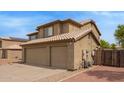 Side view of home featuring a three car garage and low maintenance desert landscaping at 12325 W Canterbury Dr, El Mirage, AZ 85335