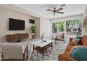 Relaxing living room features a ceiling fan, light tile floors, and a sliding glass door for natural lighting at 302 E Orange Dr, Phoenix, AZ 85012