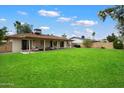 A grassy backyard with a covered patio featuring stylish furniture and a view of the home's rear facade at 6725 E Kings Ave, Scottsdale, AZ 85254