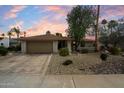 The front exterior of a single-story home with tan brick, a two-car garage, and desert landscaping at dusk at 6725 E Kings Ave, Scottsdale, AZ 85254