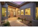 Inviting front entrance with a wooden door, desert landscaping, and ample lighting, creating a warm and stylish arrival experience at 14523 E Charter Oak Dr, Scottsdale, AZ 85259