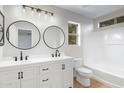 Bathroom with double vanity, round mirrors, modern fixtures, and tub shower with tile surround at 1563 S Longspur Ln, Gilbert, AZ 85296